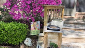 A garden with a variety of plants, a wooden bench, and a sign with a message. - 3-bedroom golf course home on Walden on Lake Conroe Montgomery with WiFi, AC (Montgomery)