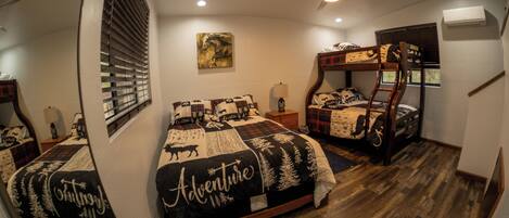 A bedroom with two bunk beds, a ceiling fan, and a window with blinds.