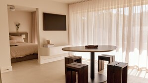 A modern bedroom with a bed, bedside table, and a round table with stools. - Noosa Parade Holiday Inn (Noosa Heads)