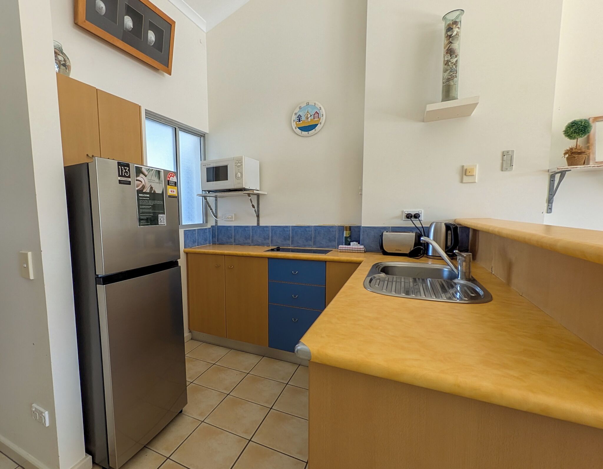 A compact kitchen with a stainless steel refrigerator, a microwave, a sink, and a small countertop.
