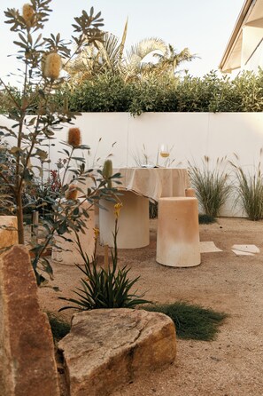 A garden with a table and chairs, surrounded by plants and rocks. - Noosa Parade Holiday Inn (Noosa Heads)