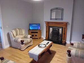 Un salon comprenant un canapé, une table basse, un téléviseur et une cheminée.