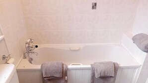Un baño con una bañera, dos toallas, un inodoro y una ducha.
