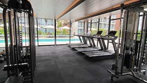 A gym with treadmills, weight machines, and a pool view. - Beachfront resort Muro Alto/Porto de Galinhas, smart apartment with pool, 4-star (Ipojuca)
