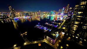 A nighttime cityscape with a marina filled with boats, illuminated buildings, and a prominent modern structure with a glass facade. - Yarra Accommodation  (Melbourne)