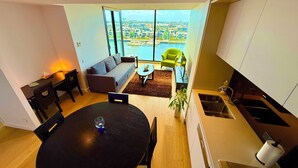 A modern apartment with a dining area, kitchen, and a large window offering a city view. - Yarra Accommodation  (Melbourne)