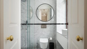 Un baño moderno con cabina de ducha de vidrio, inodoro, lavabo y espejo.