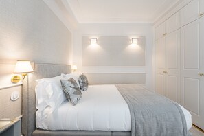 A neatly arranged bedroom with a large bed, bedside lamps, and a wardrobe.