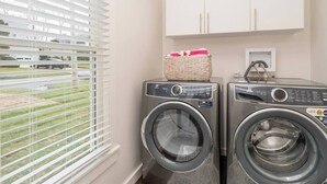 Ett tvättrum med två tvättmaskiner som man fyller på framifrån, en korg med tvätt och ett skåp ovanför.