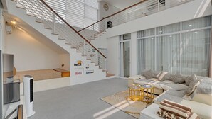 A modern living room with a staircase, a sofa set, and a flat-screen TV. -  Villa Osmanthus - Kerobokan (Kerobokan)