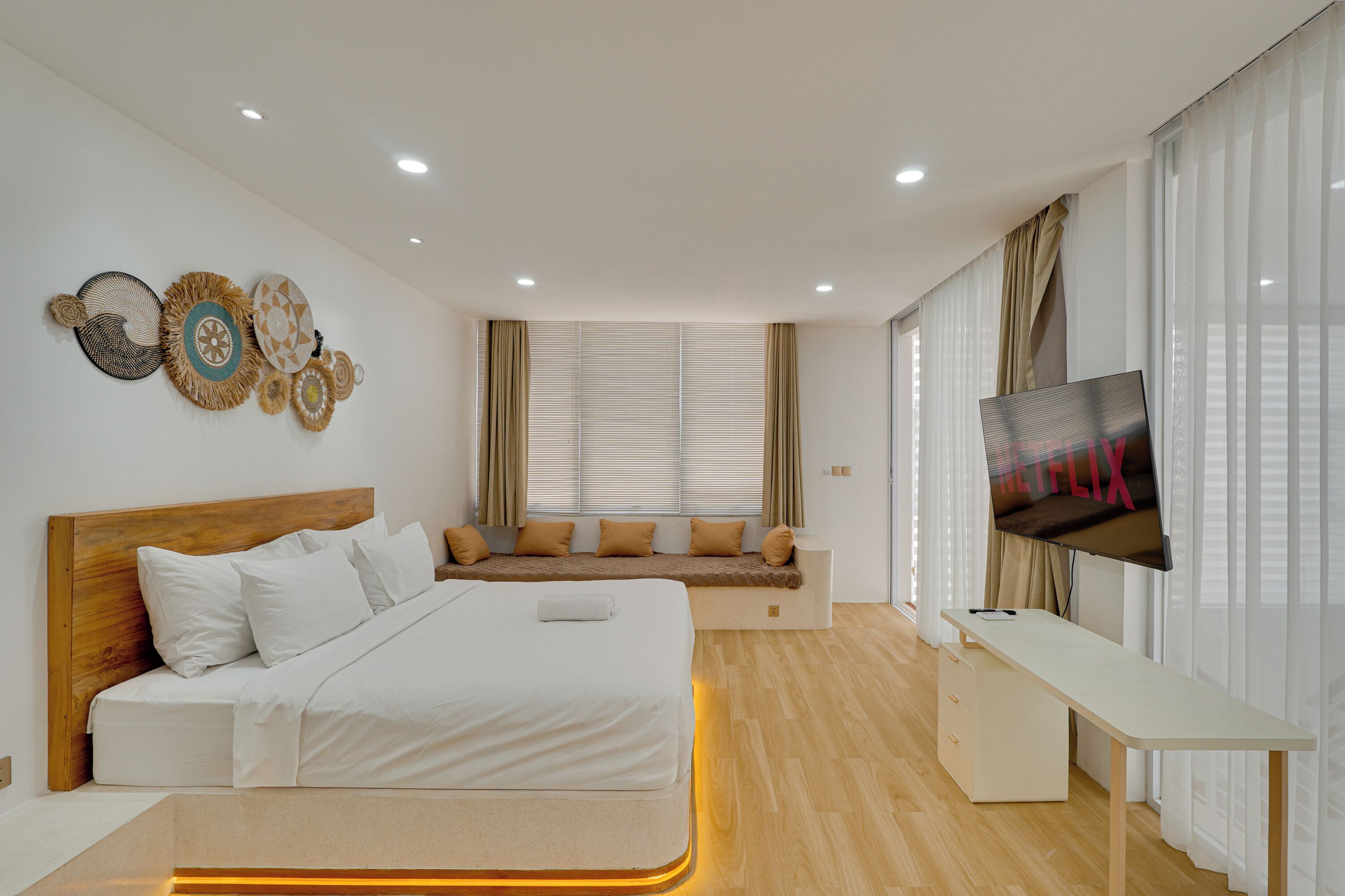 Un dormitorio moderno con cama, zona de estar, televisor y escritorio.