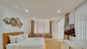 A modern bedroom with a bed, a seating area, a TV, and a desk. -  Villa Osmanthus - Kerobokan (Kerobokan)