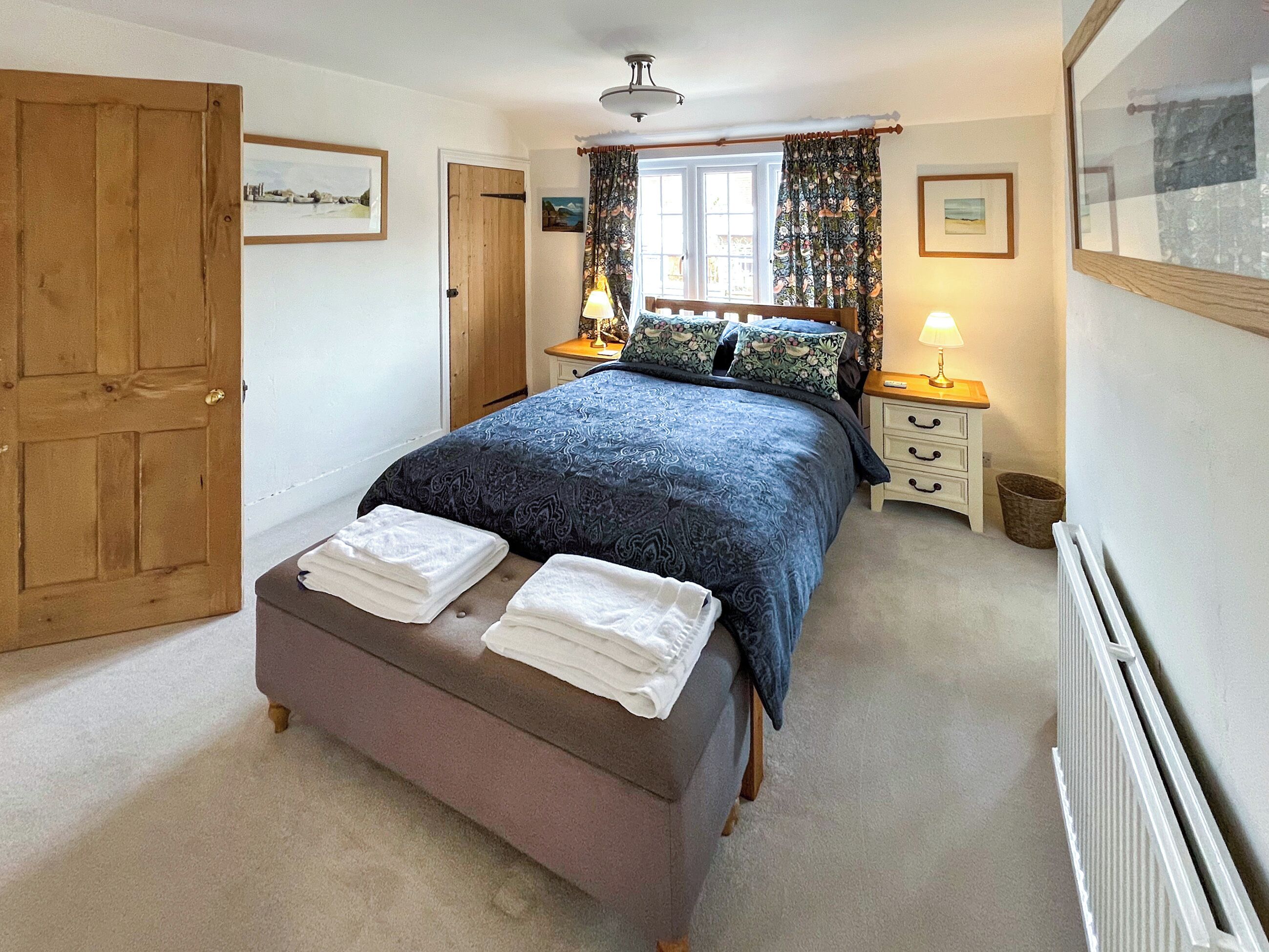 Ein Schlafzimmer mit Bett, Nachttischen, Heizkörper und Tür.