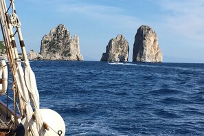 A sailboat with a view of rocky cliffs in the distance.