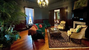 A traditional living room with a green sofa, a patterned rug, and classic furniture. - Pinwheel Place off the Square (Talladega)