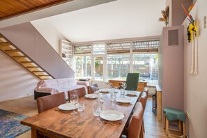 A dining area with a wooden table set for four, a sofa, and a staircase. - Family private house, 400m to the beach (Jurmala)