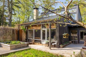 A modern house with a glass-enclosed patio, wooden deck, and outdoor seating area. - Family private house, 400m to the beach (Jurmala)