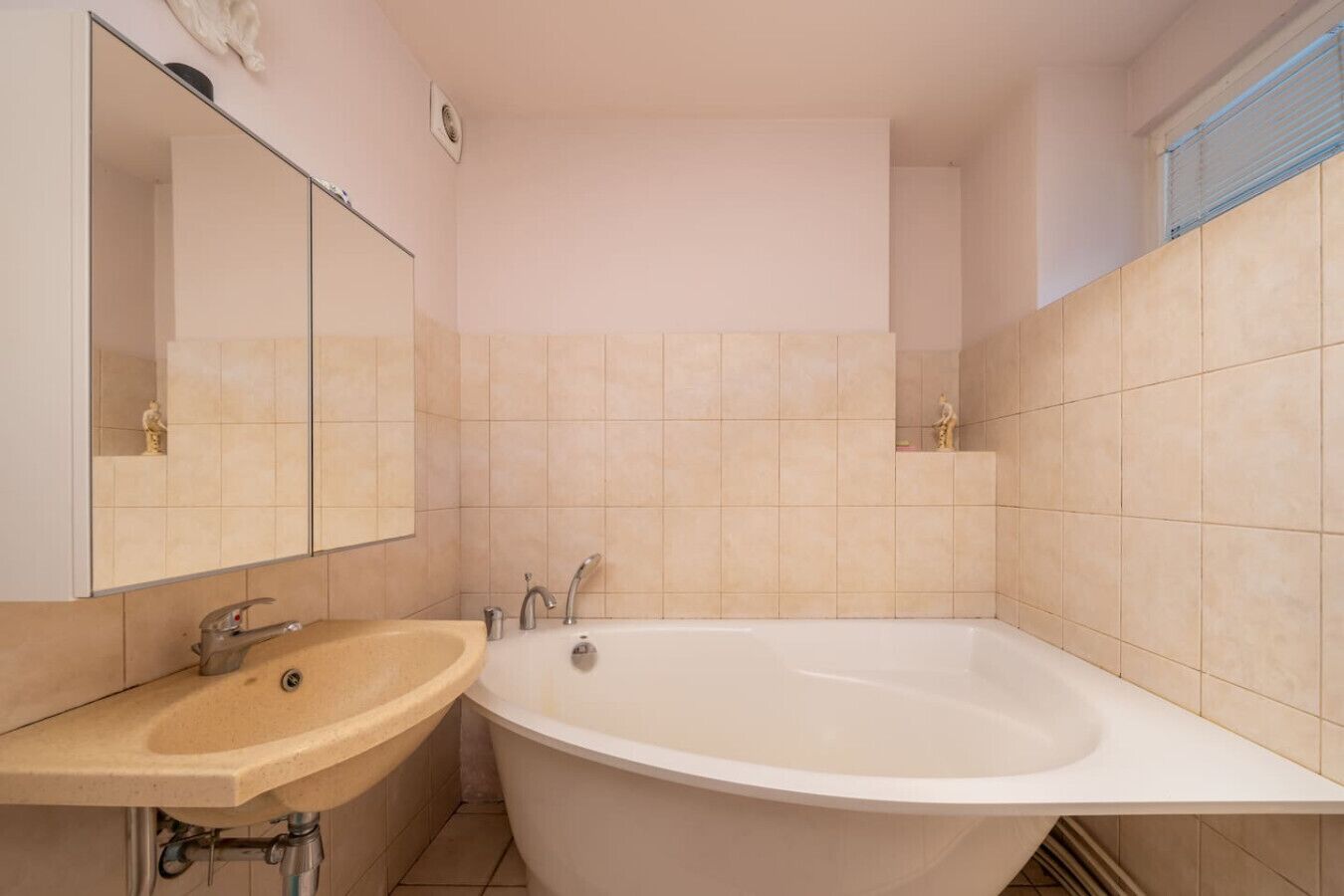 A bathroom with a freestanding bathtub, a sink, and a mirror.