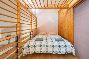 A bedroom with a wooden slatted ceiling, a bed with a patterned quilt, and a wall-mounted projector. - Family private house, 400m to the beach (Jurmala)