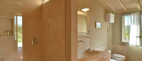 Une salle de bain avec une douche, deux lavabos, des toilettes et une fenêtre avec des rideaux.