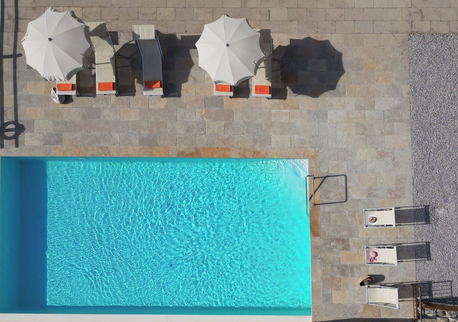 Een zwembad op het dak met helderblauw water, omringd door ligbedden en parasols.