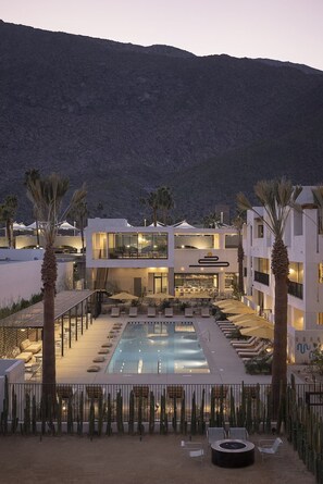 Un resort con piscina, palmeras y montañas al fondo.