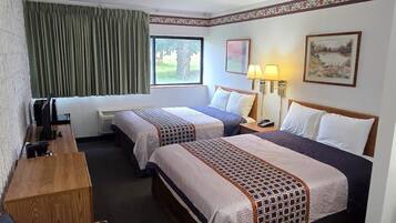 A hotel room with two beds, a desk, a chair, and a window with curtains.