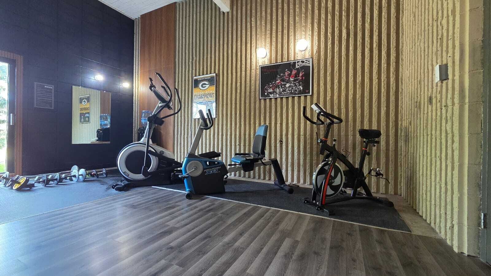 A gym with stationary bikes, a treadmill, and dumbbells.