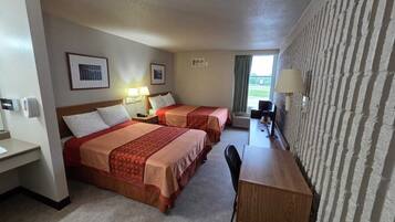 Quarto de hotel com duas camas, uma escrivaninha, uma cadeira e uma televisão.