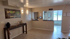 En hotellobby med en receptionsdisk, en skylt med texten ”SmartLodge Inn Osseo, Wisconsin” och ett område med inchecknings- och utcheckningsfunktioner.