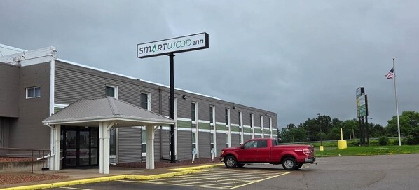A building with a sign reading "SMARTWOOD inn" and a red pickup truck parked in front. - Smartwood Inn (Osseo)