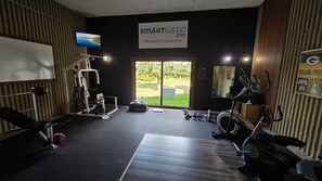 Un gimnasio con diferentes equipos de ejercicio, un televisor y un letrero que dice "SMARTWOOD inn".
