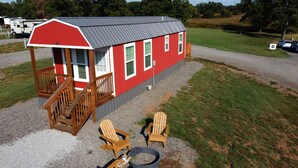 A red building with a porch, two chairs, and a table. - Redbud Roost Tiny Home (Big Cabin)