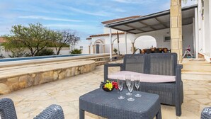 An outdoor seating area with wicker furniture and a pool in the background. - Junqué-Verdure by Interhome (Miami Platja)