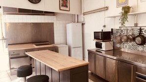 Een moderne keuken met een houten aanrecht, roestvrijstalen apparatuur en een klok aan de muur.
