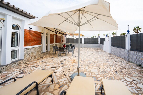 An outdoor patio with mosaic flooring, outdoor seating, and a large umbrella.