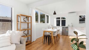 Una cocina moderna con armarios blancos, una mesa de comedor de madera y un horno empotrado.