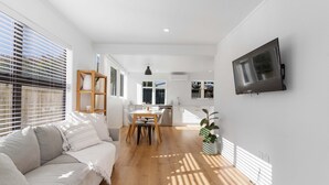 Una sala de estar moderna con un sofá, una mesa de comedor y un televisor montado en la pared.