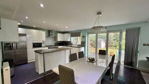 A modern kitchen with a central island, dining area with chairs, and a view of the outdoors.