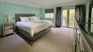 A bedroom with a bed, nightstands, a window with curtains, and a balcony.