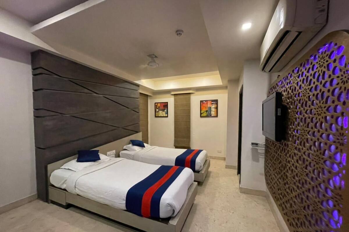 Habitació d'hotel amb dos llits, un disseny modern i una paret decorativa amb un dibuix geomètric.
