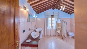 A bathroom with a wooden ceiling, a sink, a mirror, and a toilet.