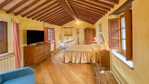 A bedroom with a wooden ceiling, a bed, a television, a dresser, and a window.