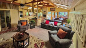 A cozy living room with a fireplace, leather sofas, and a dining area with a stone wall.