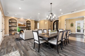A dining area with a large wooden table, six chairs, and a chandelier.