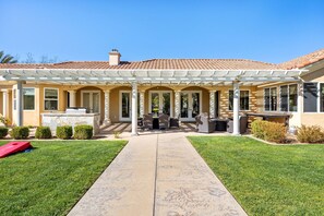 A house with a covered patio, a stone pathway, and a lawn.