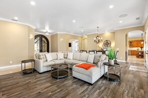 A spacious living room with a sectional sofa, round coffee tables, and a chandelier.