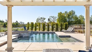 Un espace piscine agrémenté d’une pergola, de chaises longues et d’un chemin en pierre.