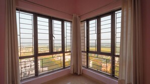 A room with two large windows, a tiled floor, and a view of buildings outside.