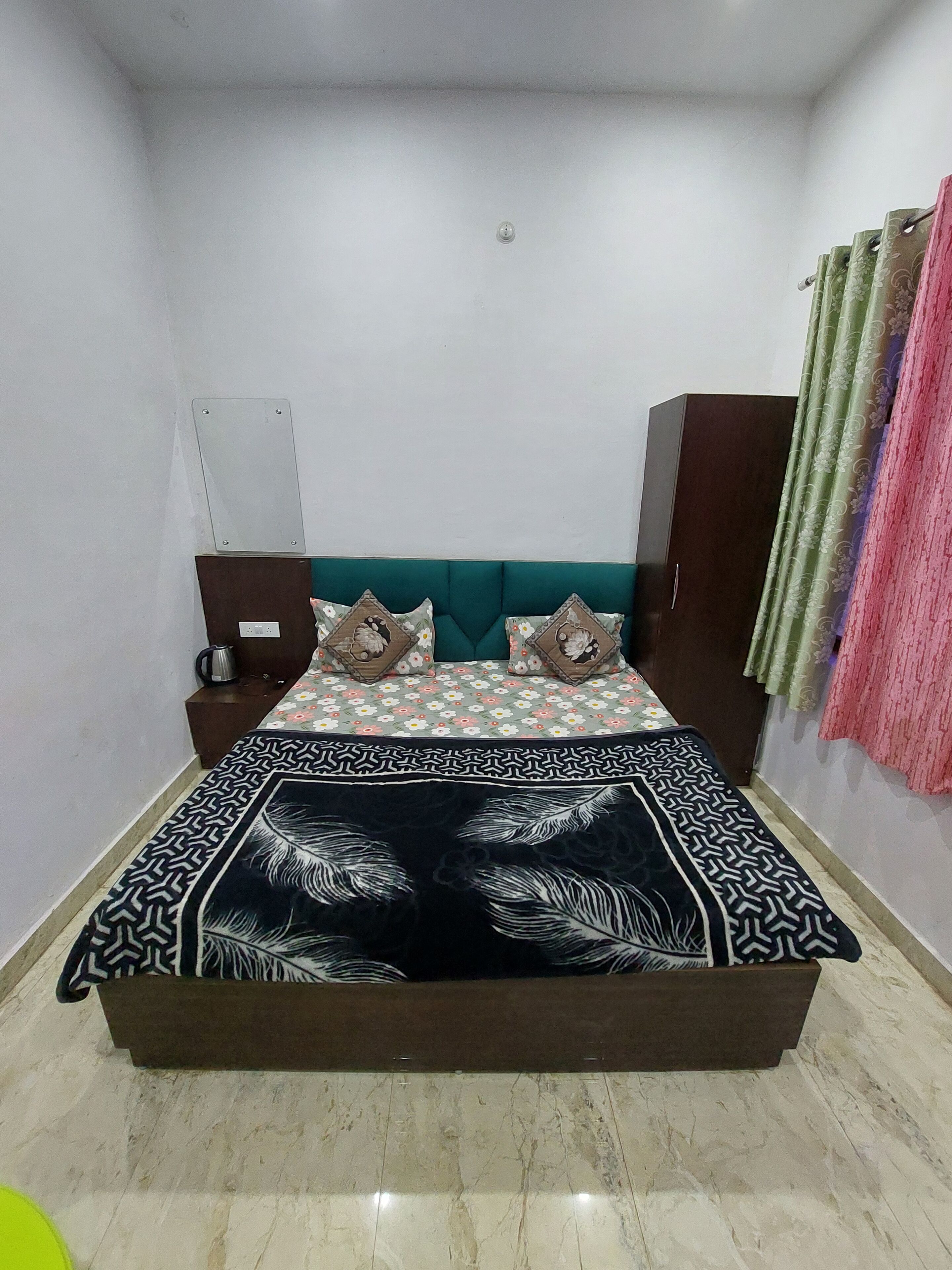 A bedroom with a bed, a nightstand, a wardrobe, and a curtain.